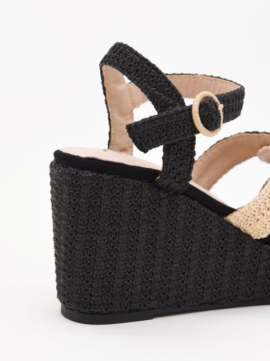 Sandalias de cuña alta en rafia negra y beige con plataforma y tiras cruzadas. Modernas, cómodas y versátiles.