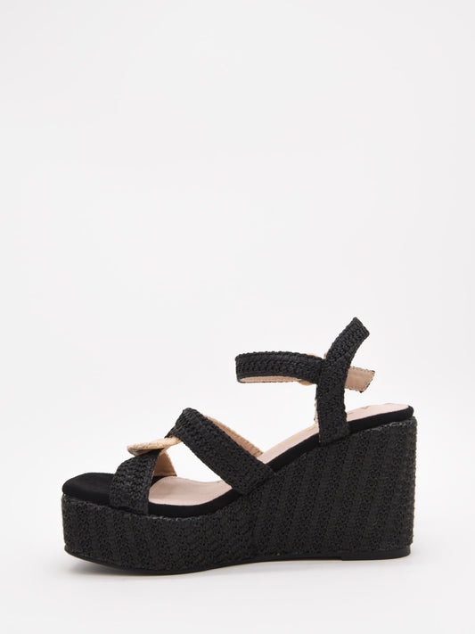 Sandalias de cuña alta en rafia negra y beige con plataforma y tiras cruzadas. Modernas, cómodas y versátiles.