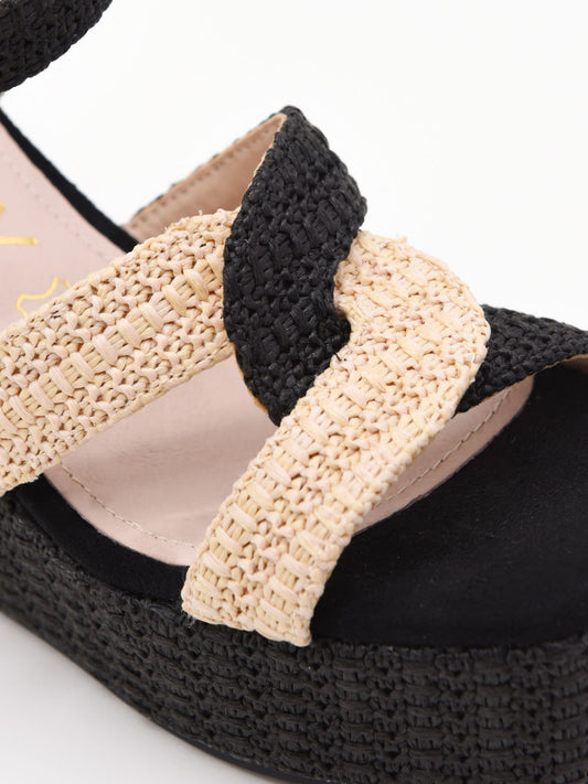 Sandalias de cuña alta en rafia negra y beige con plataforma y tiras cruzadas. Modernas, cómodas y versátiles.