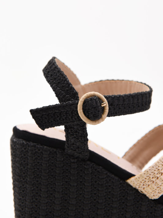 Sandalias de cuña alta en rafia negra y beige con plataforma y tiras cruzadas. Modernas, cómodas y versátiles.