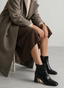 Black crocodile-effect ankle boot with buckle and heel.