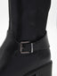 Bota alta de mujer en material sintético negro efecto piel, con hebilla lateral y tacón bajo ancho.