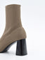Botín taupe de tejido elástico tipo calcetín con caña media ajustada y tacón ancho geométrico en negro.