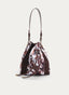 Bolso bombonera de silueta tipo saco en tonos marrón, blanco y negro, con estampado de inspiración animal. Presenta paneles marrón oscuro, cierre superior mediante cordones, asa larga de hombro, correa adicional y herrajes dorados.