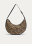 Bolso de hombro de silueta curva tipo media luna, con estampado de leopardo en tonos beige y negro. Presenta ribetes y asa negra regulable con hebilla dorada, además de cierre superior mediante cremallera dorada.