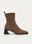 Botín de mujer en color camel con caña ajustada tipo calcetín, puntera cuadrada y tacón geométrico negro de altura media. Presenta tirador trasero negro y diseño limpio de líneas modernas y elegantes.