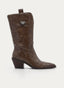 Bota cowboy de mujer en color taupecon caña media-alta, puntera afilada y tacón ancho inclinado. Presenta tirador superior con detalle metálico decorativo, costuras visibles, cremallera lateral y silueta western elegante.