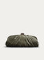 Bolso clutch alargado en color verde oliva, con diseño fruncido y volumen suave. Presenta cierre metálico dorado en la parte superior y cadena fina dorada desmontable para llevar al hombro.