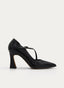 Zapato de salón femenino en color negro, con punta fina, abertura lateral y tira cruzada sobre el empeine de un lado a otro. Presenta hebilla metálica ajustable y tacón alto ancho con base ligeramente acampanada.